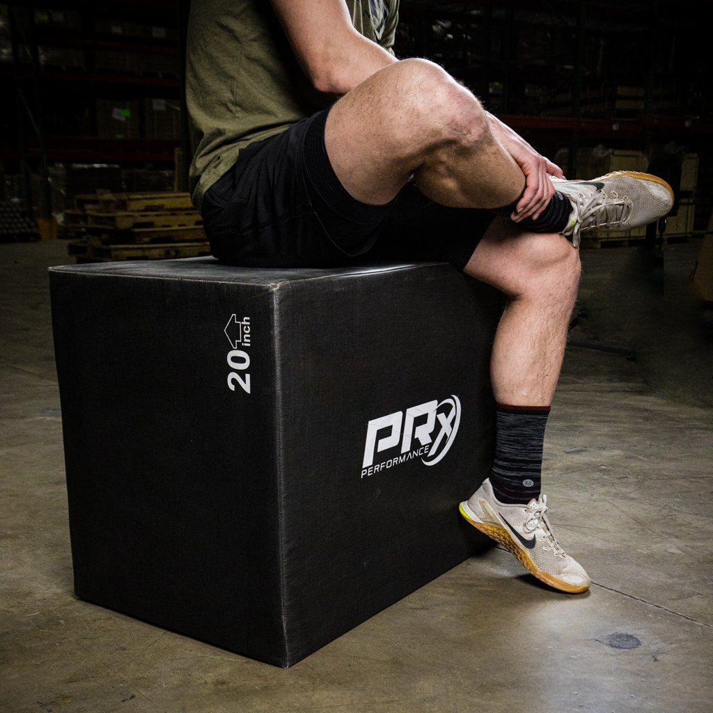 Person sitting on a PRX soft plyo box in a warehouse setting